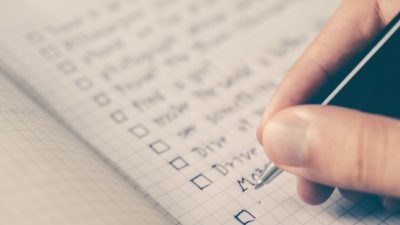 Photo of a hand writing down a checklist in a notebook