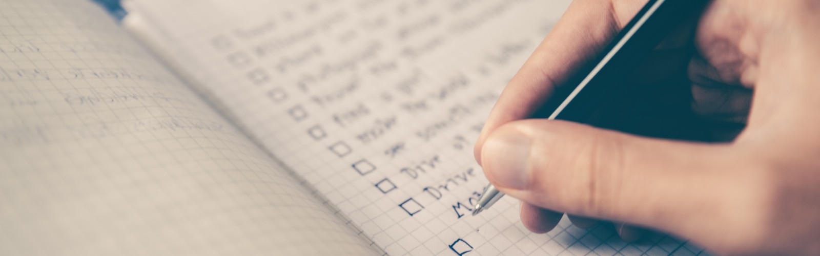 Photo of a hand writing down a checklist in a notebook