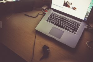 Photo of a desk with a mac laptop on the table with a key below it