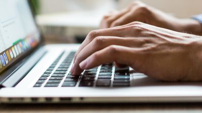 Photo of a person typing on the laptop