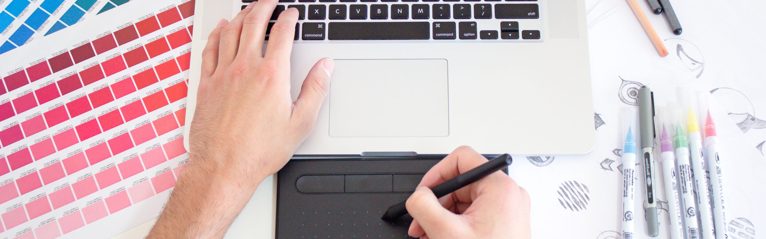Photo of left handing typing on a macbook and right hand drawing using a digital pen
