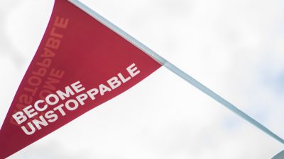 Photo of Uni of Salford tagline 'Become Unstoppable' written on a red decorative flag