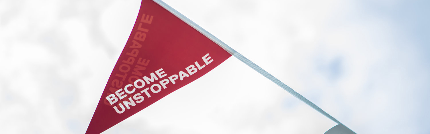 Photo of Uni of Salford tagline 'Become Unstoppable' written on a red decorative flag