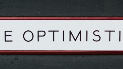 Photo of text "Be Optimistic" written in Black Capital Letters in a White Background