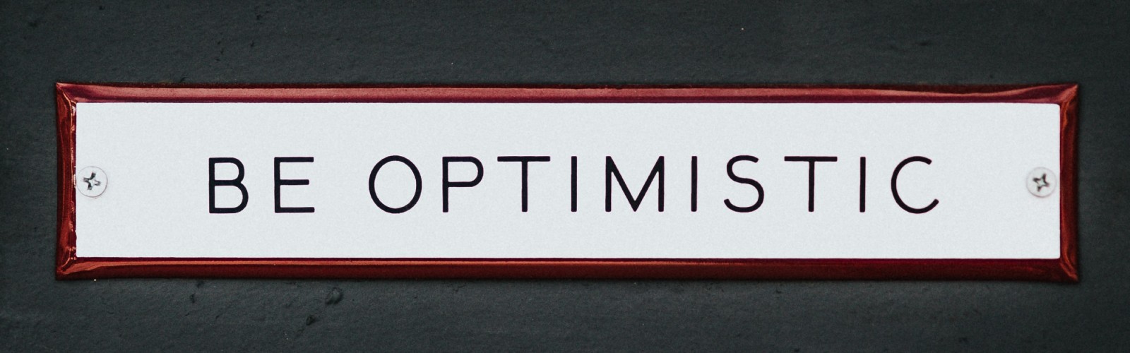 Photo of text "Be Optimistic" written in Black Capital Letters in a White Background