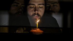 Jack sat in darkness blowing out a candle on a muffin. The image is mirrored showing his face either side of him.