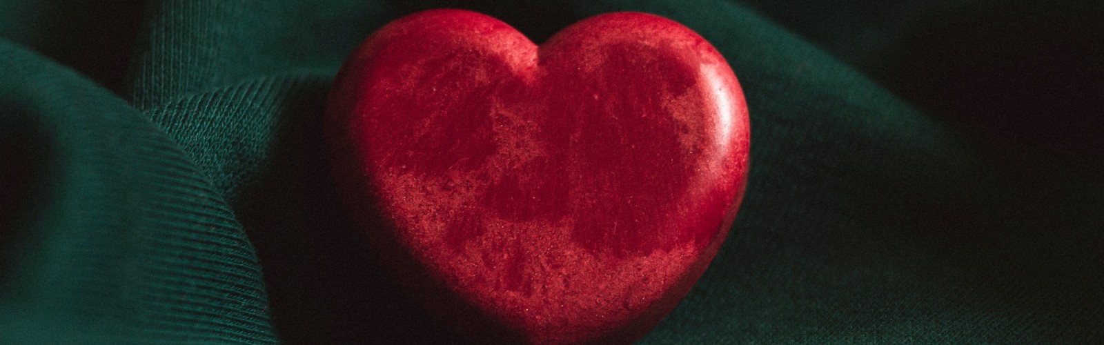 Photograph of a red stone heart on a green background