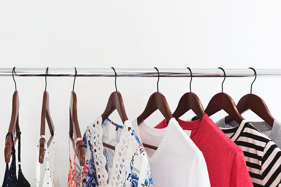 photo of different colored clothes on a rail hanging against a white background