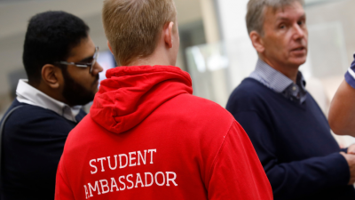 Photo from the back with the volunteer wearing the University of Salford red student ambassdor hoodie