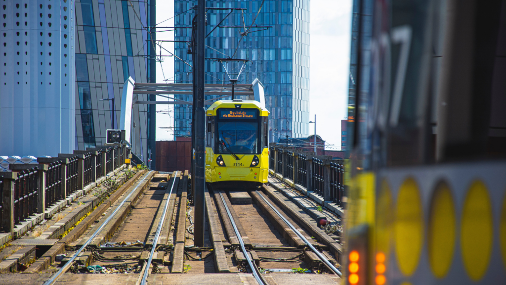 A Greater Manchester Metrolink tram with skyscrapers in the background