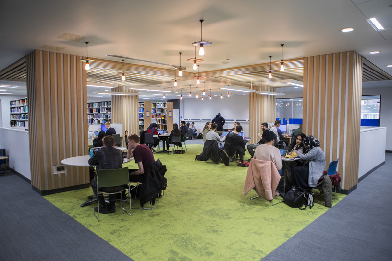 students in groups sitting and discussing inside the library