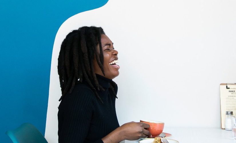 Image of a woman and man against a blue and white background drinking and laughing.