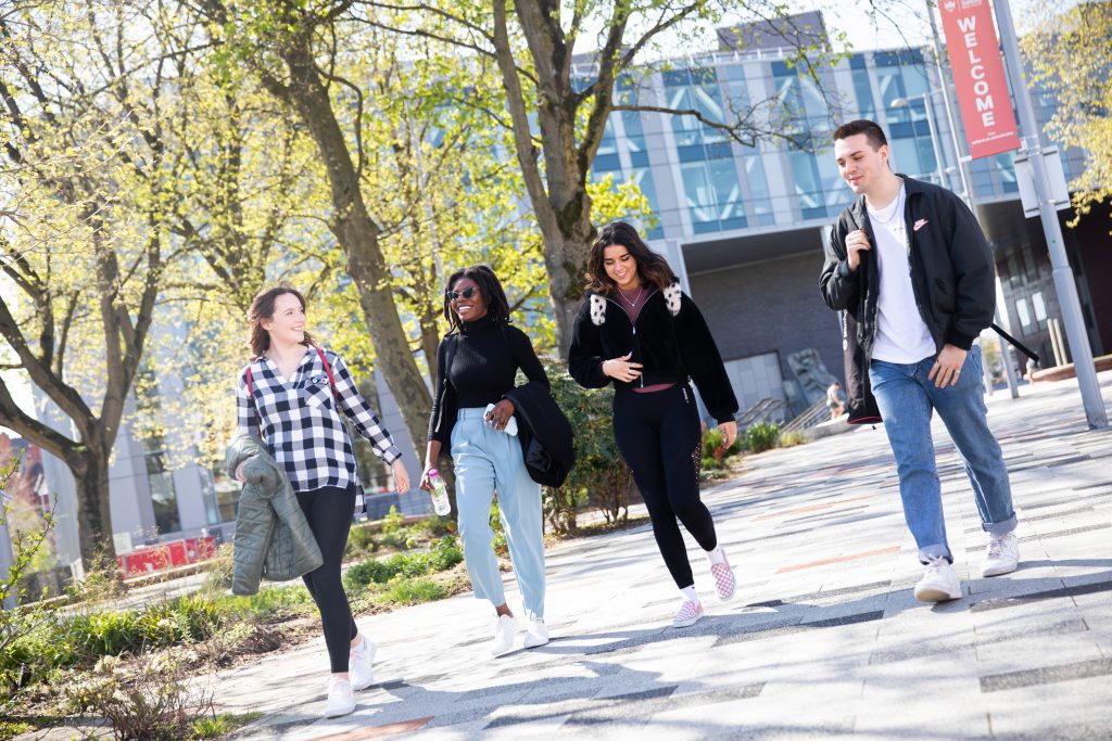 Photo of Niamh walking with her friends in Salford uni main campus