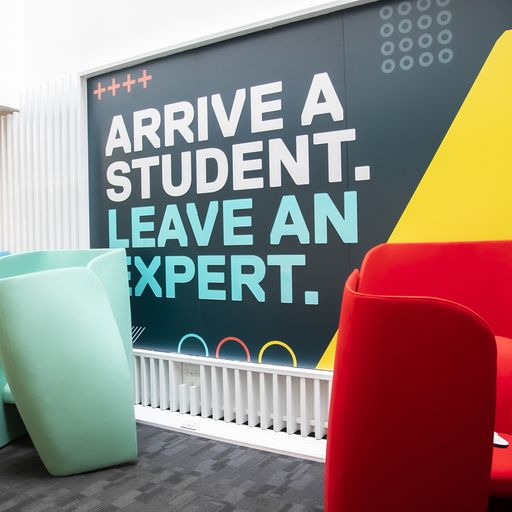 Photo of a sign on the wall reading "Arrive a student, leave an expert."