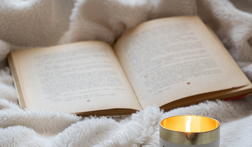 An open book next to a lit candle