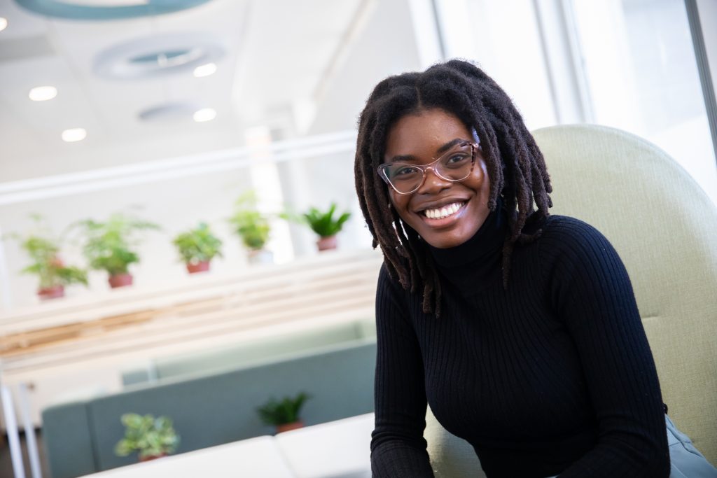 Chidera, a postgraduate student at the University of Salford seated and smiling 