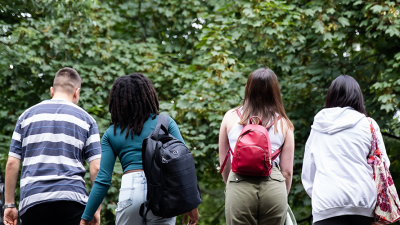 Photo of people walking together on the bridge with trees in the background.