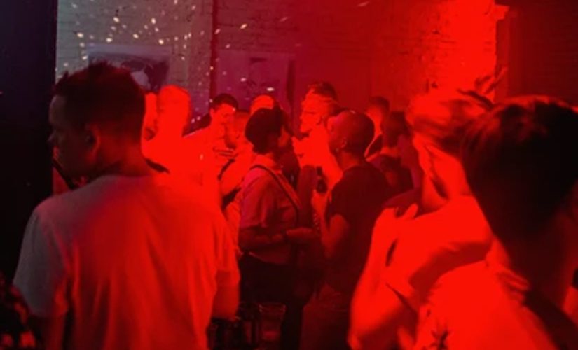 Photo of people inside a venue with red neon lighting