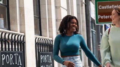 Photo of 2 girls laughing looking at each other on the sidewalk