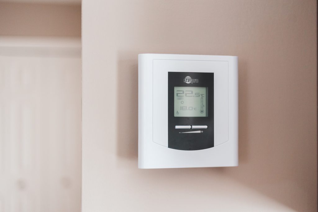 photo of a white and gray thermostat on the wall