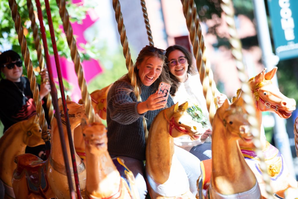 Two people riding a carousel at Welcome Week at the University of Salford.