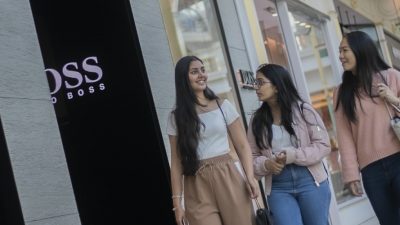 Photograph of three people walking close together in a shopping centre.