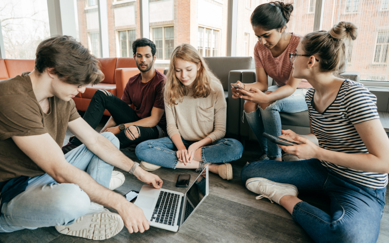 Students sat in a circle on their laptops and mobile phones