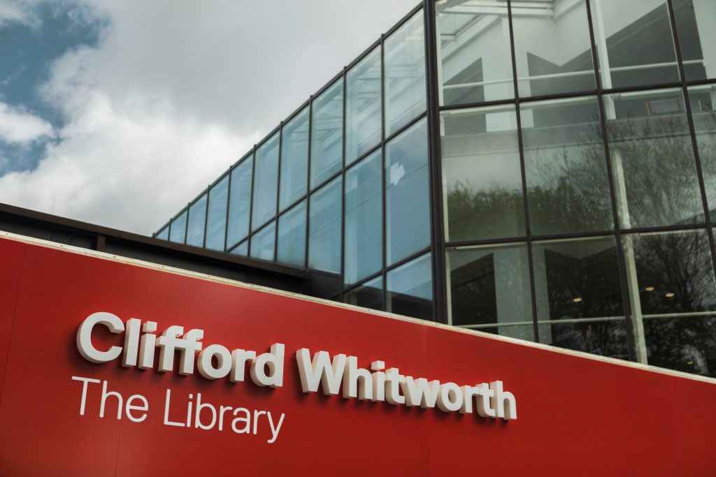 Photo of the sign above the University's library, sign reads: Clifford Whitworth. The Library.