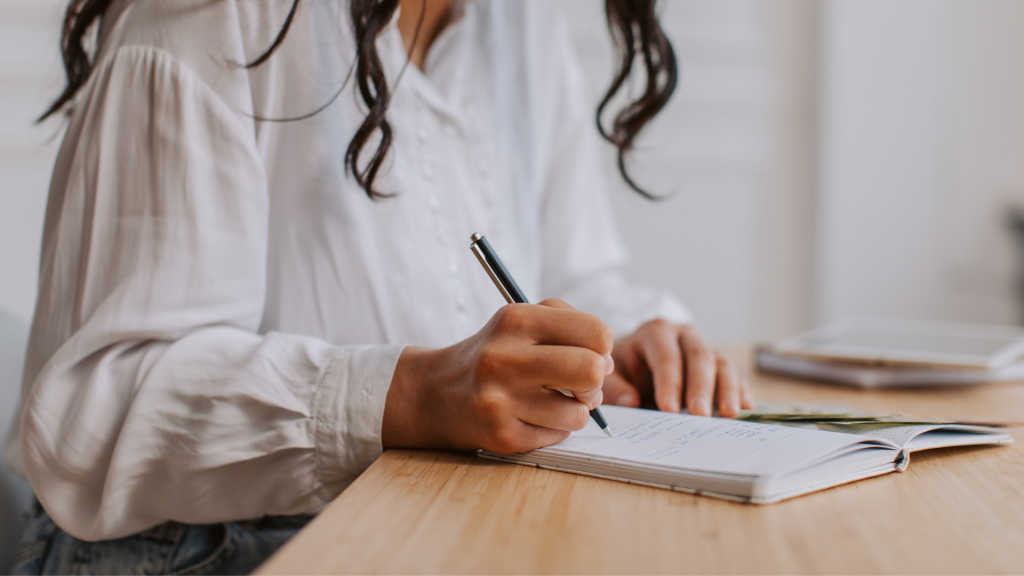 Photo of a person writing in the a notebook