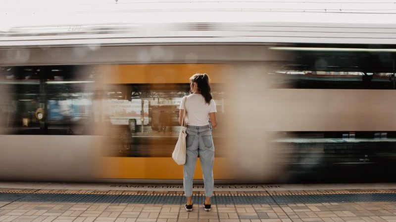 Student stood on a train platform as a train passes by