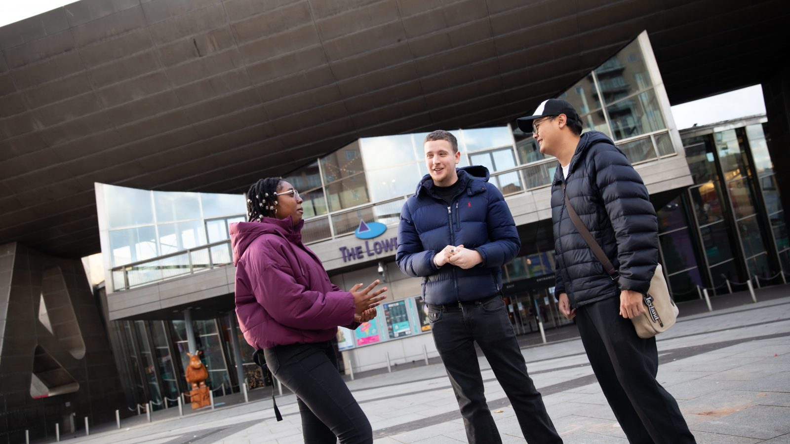 Three students stood talking outside of the Lowry theatre