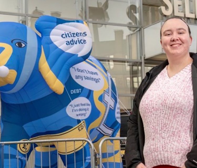 Student looking towards the camera standing in front of an inflatable elephant