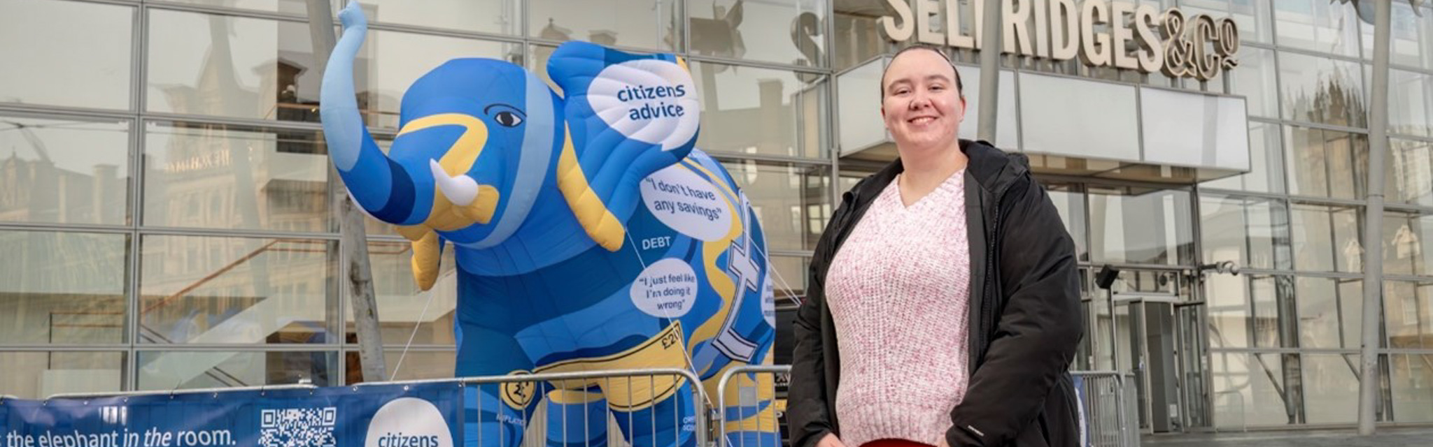 Student looking towards the camera standing in front of an inflatable elephant