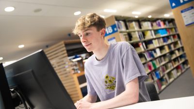 Student sat at a computer in the library