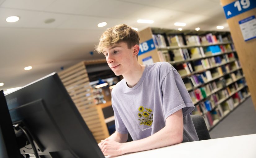 Student sat at a computer in the library