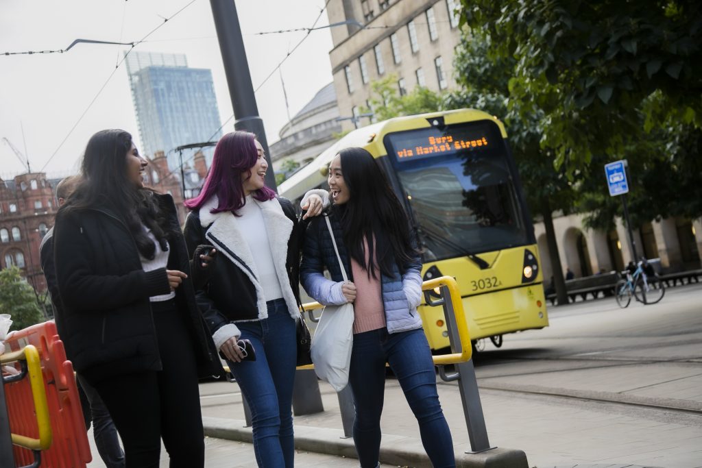 Three students walking alongside a tram