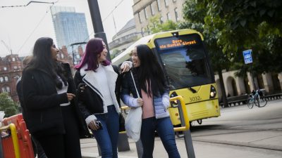 Three students walking alongside a tram