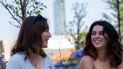 Two students talking outside in the summer sunshine.