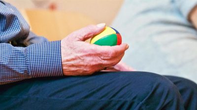 Elderly individual holding a weighted ball in one hand