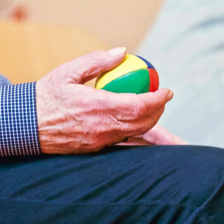 Elderly individual holding a weighted ball in one hand