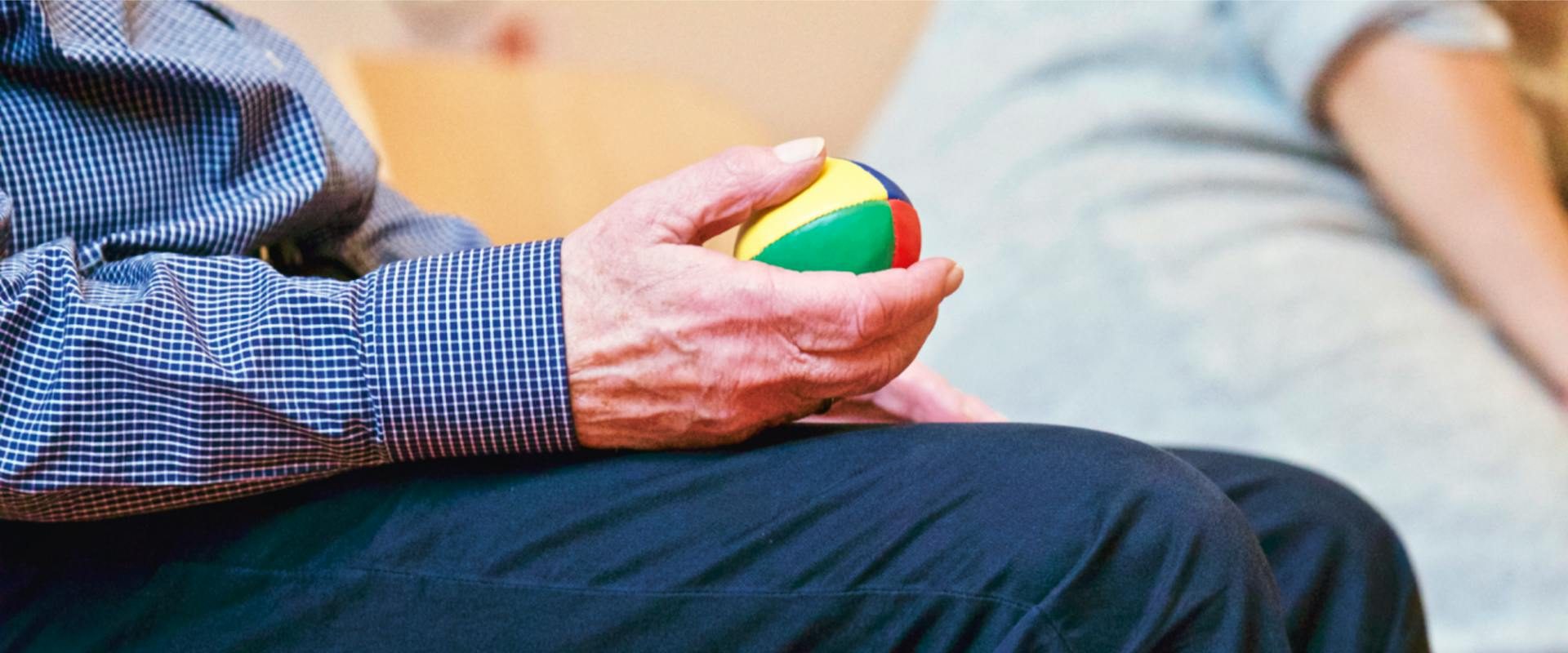 Elderly individual holding a weighted ball in one hand