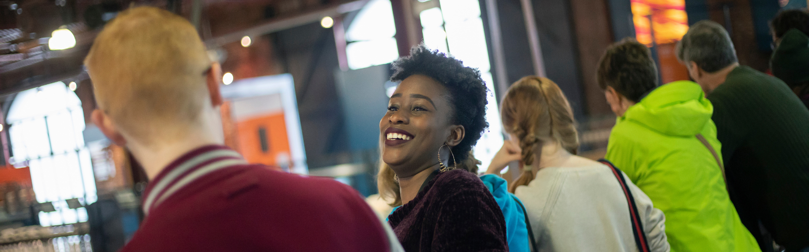 Two students are speaking to each other. One has their back to the camera, while the other is visible and laughing.