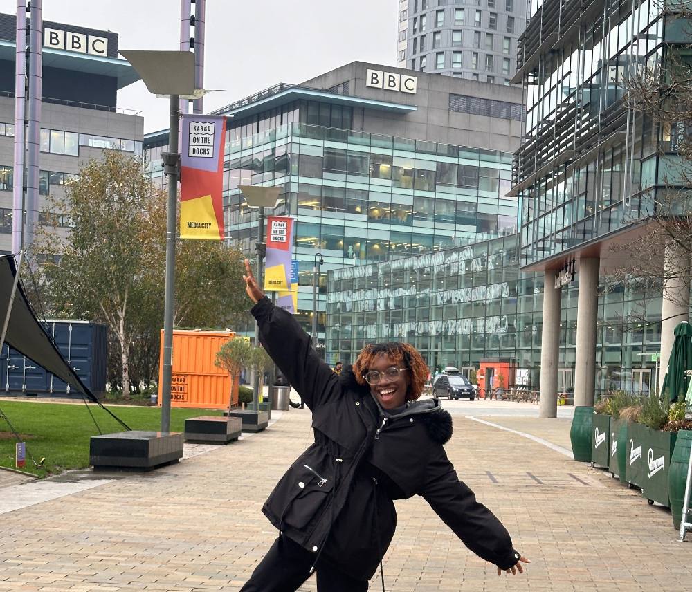 Truth with her arms outstretched posing in front of the BBC building at MediaCity