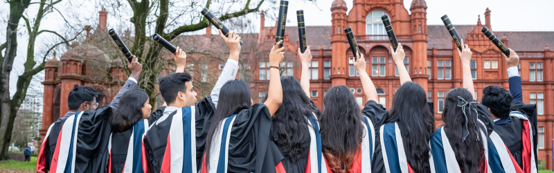 A group of students at graduation holding up their scrolls