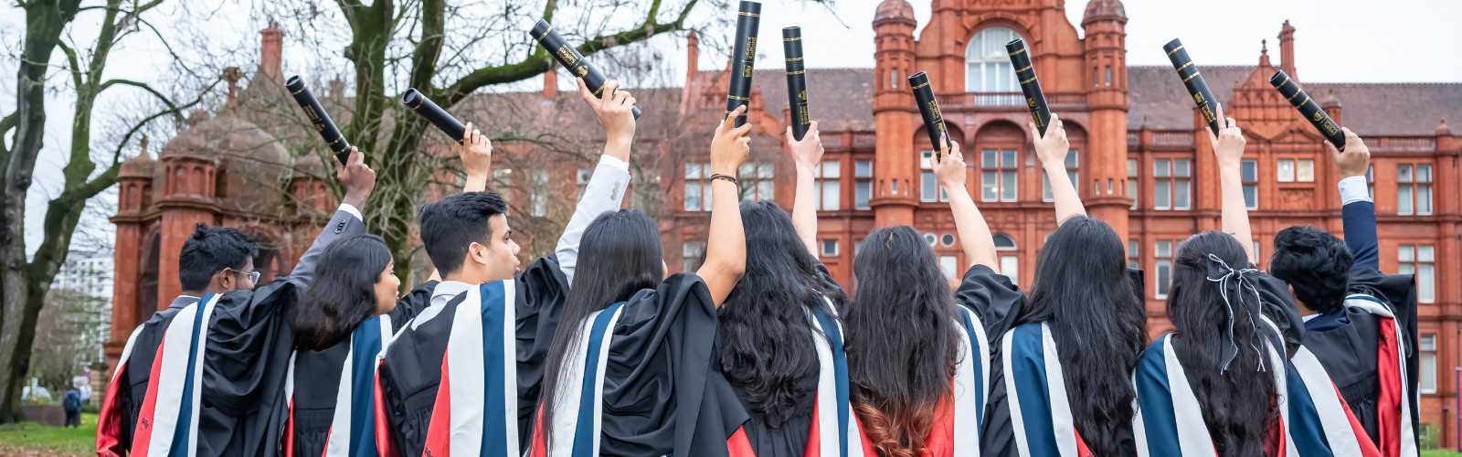 group of students at graduation holding up their scrolls