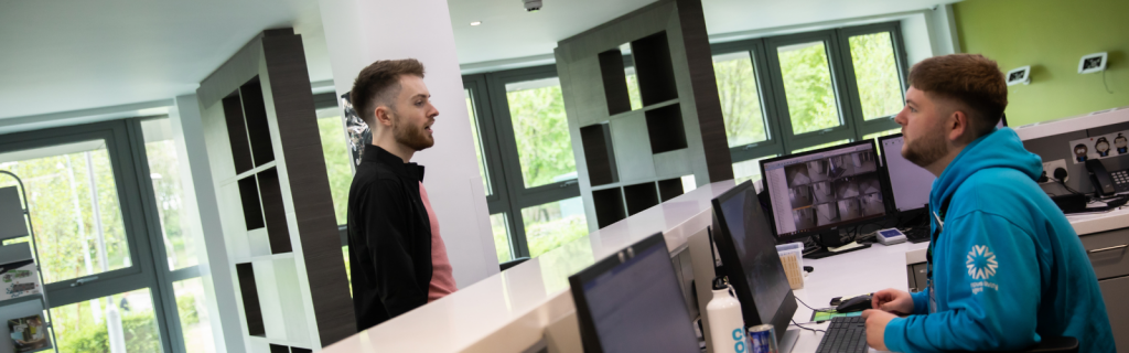 A student is speaking with a member of staff at a desk.