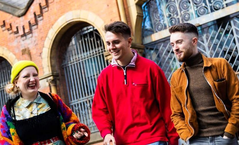 Three students laughing and walking outside in Manchester City