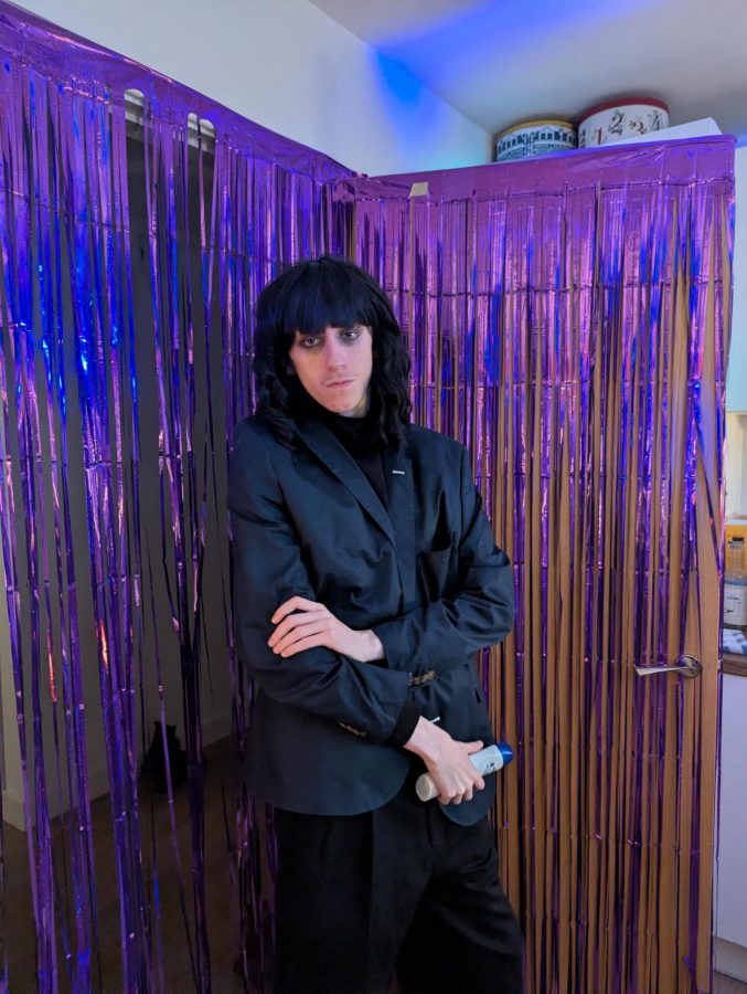 Josh in a black fringed wig & turtleneck, dressed up as Claudia Winkleman