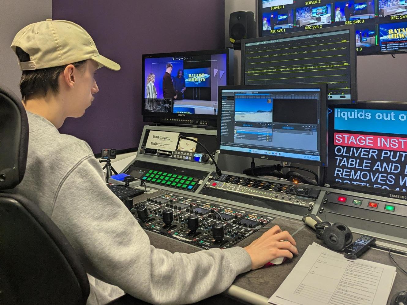Josh sitting behind the desk in the TV studio gallery