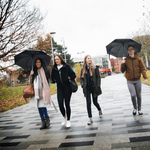 Students walking on campus with umbrellas